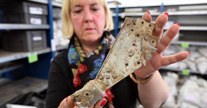 Archaeologist Tünde Kaszab-Olschewski holds in her hands parts of a British bomber that crashed in Germany in 1943. Credit: Federico Gambarini/dpa